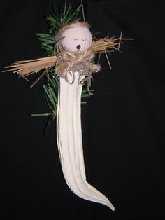 a doll hanging from a string on top of a black background with green leaves and branches