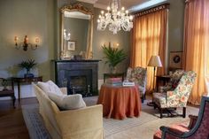 a living room filled with furniture and a chandelier hanging from the ceiling over a fire place