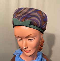 "This is a sweet vintage tall pillbox style hat that dates from the early 60s. No brand labels, only a Union label. It measures 21\"around the inside & is 3-1/2\" tall. Made of forest green, purple & brown fabric. The bottom edge is green grosgrain ribbon as is the flat bow trim. The hat is in good, vintage condition. No soil & minimal wear. Nice!" Retro Fitted Cloche Hat, Retro Adjustable Cloche Hat With Curved Brim, Vintage Green Mini Hat With Short Brim, Retro Mini Hats With Curved Brim, Green Vintage Mini Hat With Short Brim, Brown Vintage Cloche Hat, Retro Adjustable Cloche Hat, Fitted Retro Green Hat, Retro Fitted Green Hat