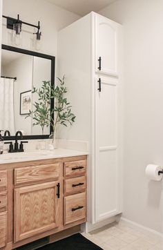 a bathroom with white walls and wooden cabinets