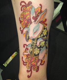 a rabbit tattoo on the leg of a woman with flowers around her neck and legs