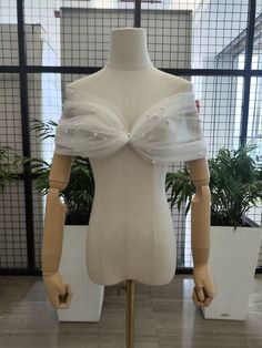 a mannequin wearing a white dress with pearls on it's chest and shoulder