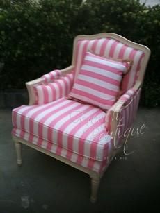 a pink and white striped chair with pillows