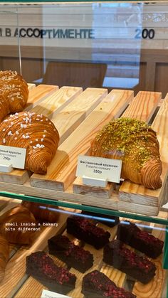 some breads and pastries are on display in a glass case at a bakery