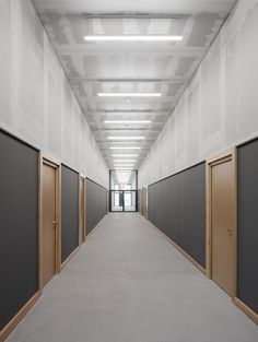 an empty hallway with closed doors and white walls