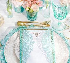 a table set with place settings and flowers in vases