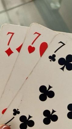 four playing cards being held up in the air