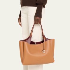 Tod's "Apa" tote bag in leather  Flat shoulder strap with logo charm  Open top with lobster clasp closure  Interior, two zip compartments  Approx. 10.2"H x 16.1"W x 7.4"D Made in Italy Luxury Tan Shoulder Bag With Double Handle, Tan Satchel With Gold-tone Hardware And Double Handle, Timeless Cognac Shoulder Bag With Palladium Hardware, Tan Top Handle Shoulder Bag, Luxury Tan Shoulder Bag For Everyday, Cognac Tote Shoulder Bag With Palladium Hardware, Cognac Bags With Palladium Hardware, Calf Leather Tote Shoulder Bag For Travel, Cognac Calf Leather Shoulder Bag With Double Handle