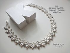 a white necklace with pearls on it and a small box in the background that says, diy schma - pattern italian - english merloto