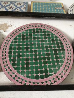 a green and pink plate sitting on top of a white wall next to other plates