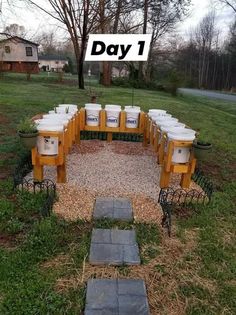 a bunch of buckets sitting on top of a wooden bench in the middle of a field