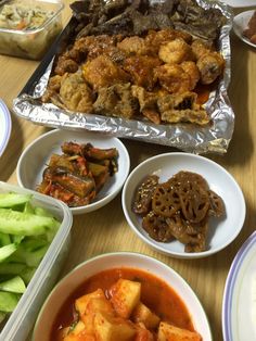 a table topped with plates and bowls filled with food next to other dishes on top of a wooden table