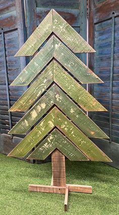 a wooden christmas tree sitting on top of green grass