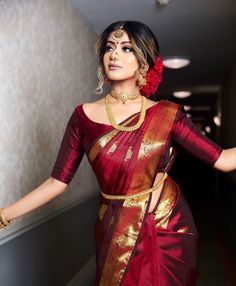 a woman in a red and gold sari posing for the camera with her hands on her hips