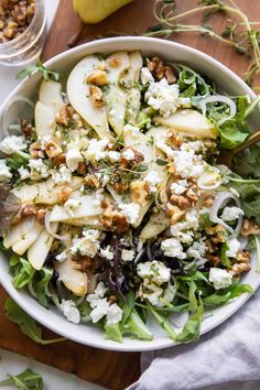 a salad with pears, feta cheese and walnuts in a white bowl