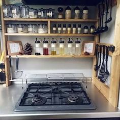 a stove top oven sitting inside of a kitchen next to shelves filled with cooking utensils