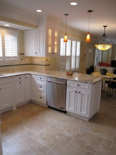 a large kitchen with white cabinets and marble counter tops, along with an island in the middle