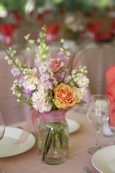 a vase filled with lots of flowers sitting on top of a white tablecloth covered table