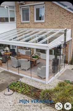 a glass house with patio furniture in front of it and the words mini vera on the side