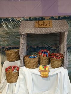 several baskets are sitting on a table with a market sign in the middle and other items around it