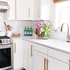 a kitchen with white cabinets and pink flowers