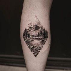 a man's leg with a mountain landscape tattoo on the side of his calf