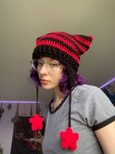 a woman with purple hair wearing a black and red crocheted beanie hat