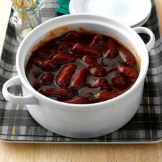 a white bowl filled with red beans sitting on top of a wooden table next to a plate