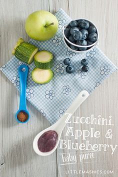 blueberries, apples and cucumbers on a towel with spoons next to them