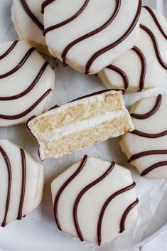 a white plate topped with cut in half cookies covered in frosting and chocolate stripes