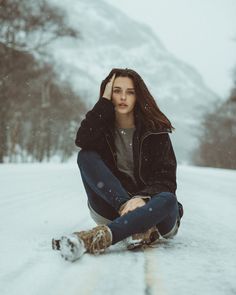 a woman sitting in the snow with her hand on her head