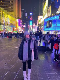 a woman is walking down the street at night in times square, new york city