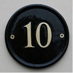 a black and gold plaque with the number 10 on it's side, in front of a white background