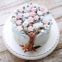 a cake decorated with pink flowers on top of a white plate and wooden flooring