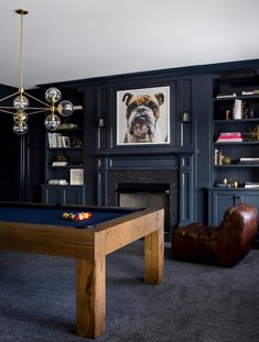 a living room with a pool table, fireplace and bookshelf in it's center