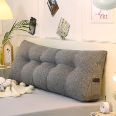 a bed with a gray pillow on top of it next to a lamp and pictures