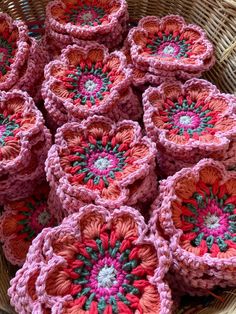 many crocheted pink and red flowers in a basket