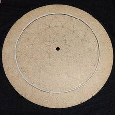 a white circular object sitting on top of a black cloth covered tablecloth with holes in the center