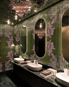 two sinks and mirrors in a bathroom with green wallpaper on the walls, along with other fixtures