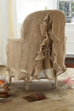 a chair that is sitting in front of a window with a book on the floor next to it