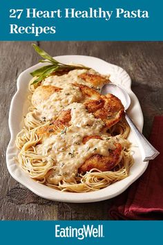 a white plate topped with pasta covered in sauce and chicken breast patties next to a red napkin