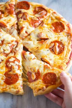 a person holding a slice of pepperoni pizza