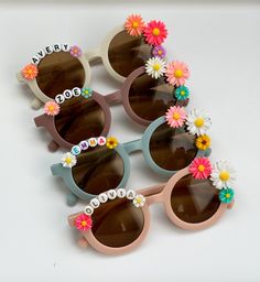 several pairs of sunglasses with flowers on the lens and name written on them, all in different colors