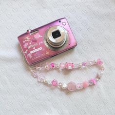 a pink camera sitting on top of a table next to a white cloth covered floor