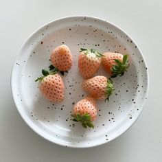 five strawberries on a white plate with sprinkles