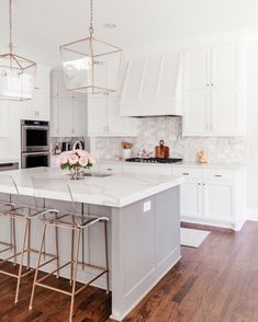 a large kitchen with white cabinets and marble counter tops, an island in the middle