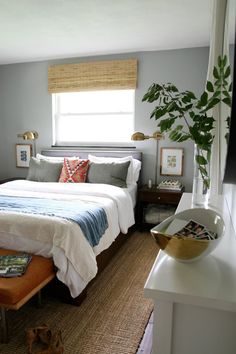 a bedroom with a bed, nightstands and a plant in the window sill