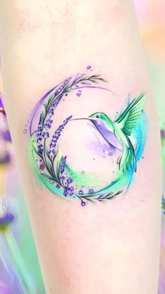 a tattoo on the leg of a woman with a hummingbird and lavenders around it