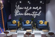 a room with couches, chairs and neon signs on the wall that says you are more than beautiful