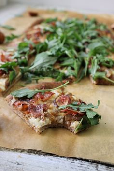 the pizza is topped with fresh greens and ready to be cut into bite sized pieces